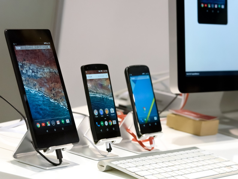 desktop monitor next to three smart phones